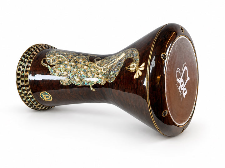Sala Amber Peacock Sombaty ダルブッカを横に置き、濃い琥珀色のモザイクの背景に Sala ブランドのドラムヘッドと淡い孔雀のモチーフを示しています。