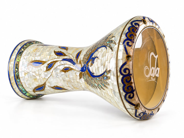 Sala Phoenix Pearl Sombaty ダルブッカを横に置き、Sala ブランドのドラムヘッドと淡いモザイクに広がる青と金の鳥のモチーフを示しています。